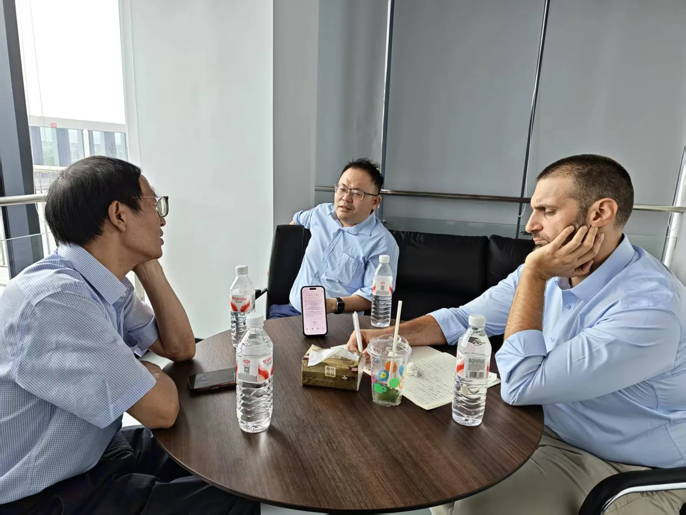 Three people discussing business around a meeting table