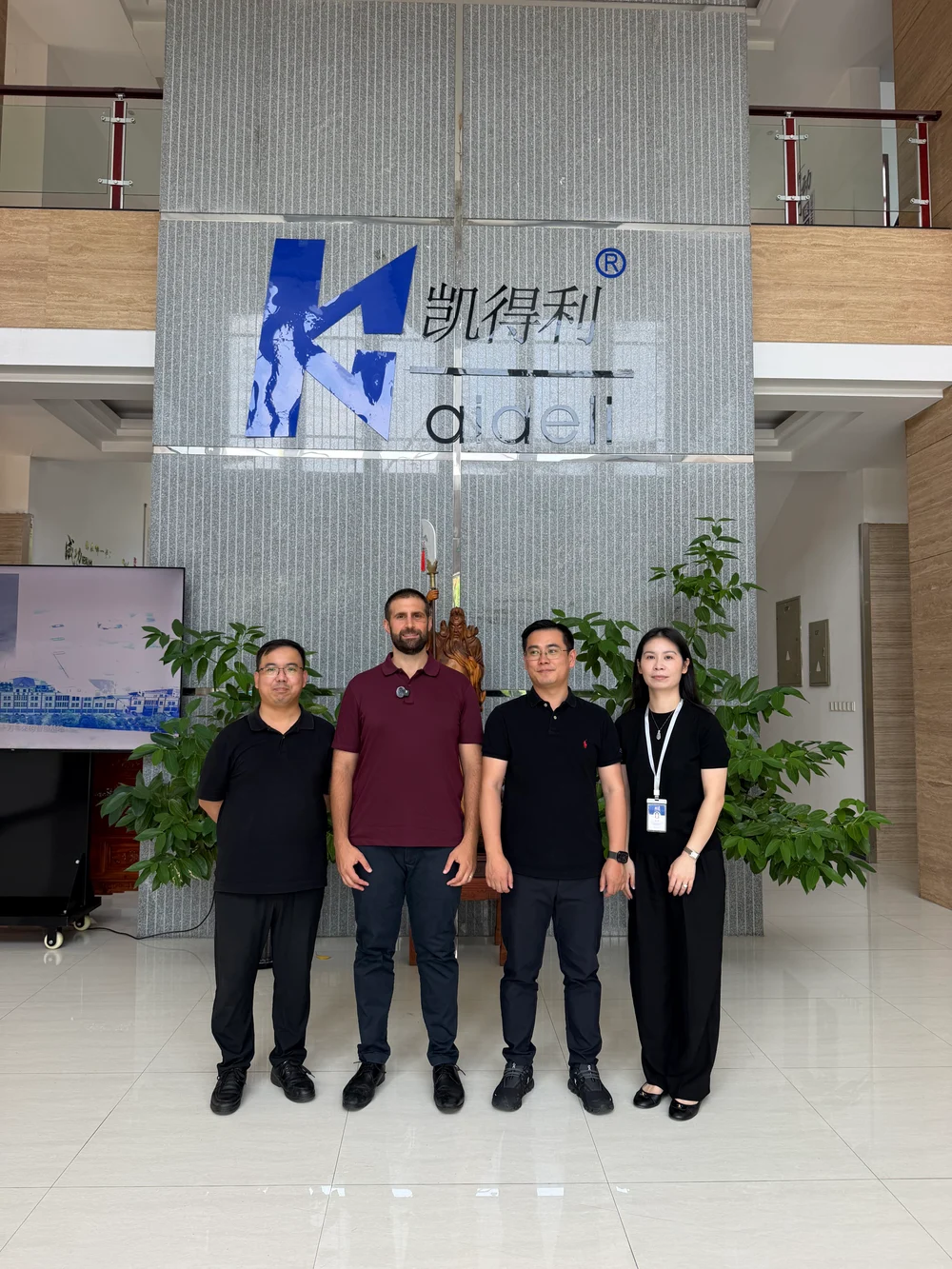 Four people posing in the Kaideli company lobby